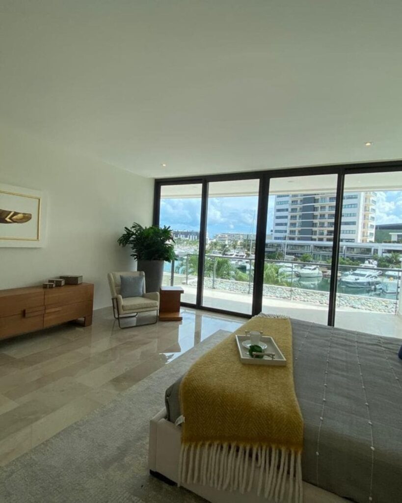 Dormitorio moderno con ventanales de piso a techo en departamento exclusivo en Puerto Cancún Cancún