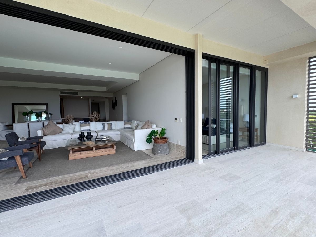 Sala y comedor con ventanales y vista al mar en departamento exclusivo en La Vela Puerto Cancún